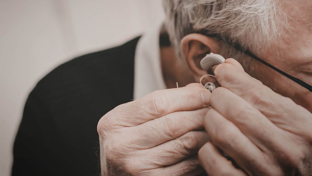 Iäkäs henkilö kiinnittää kuulokojetta korvaan