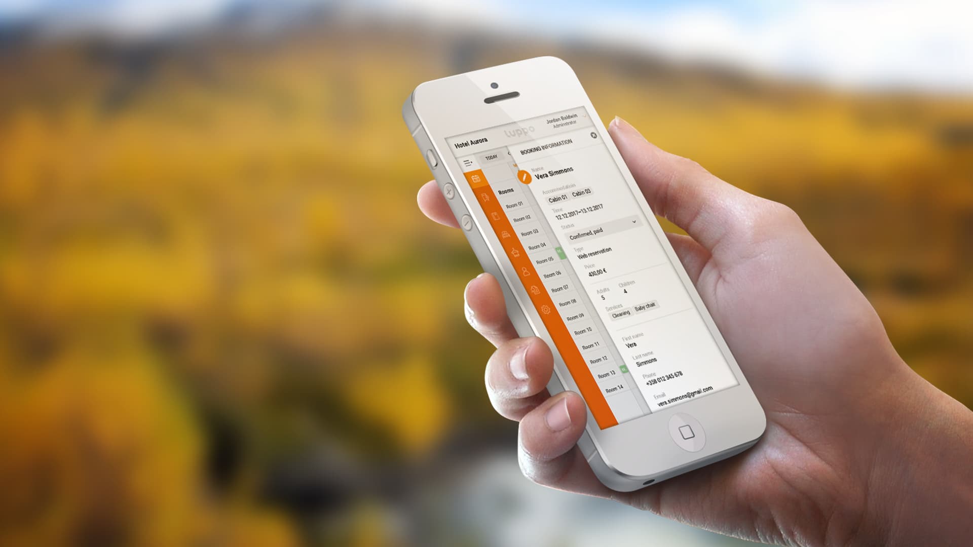 Matkapuhelin kädessä ruskamaisemassa jossa auki verkkopalvelu