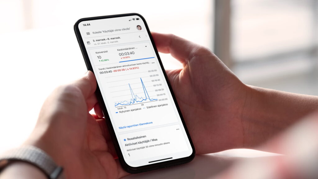 Nainen pitää mobiililaitetta kädessä jossa auki analytiikka